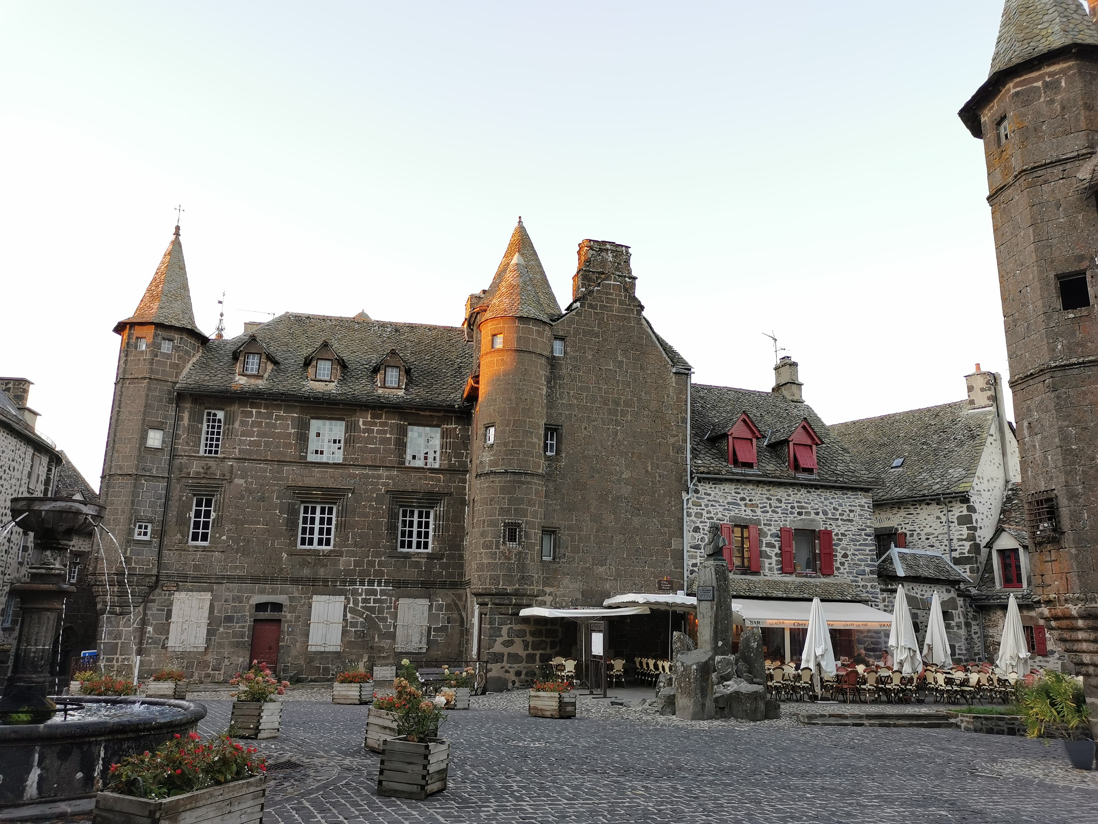 Maisons en pierre noire de basalte de Salers, Cantal, avec leurs tourelles et leurs toits en lauze sous lumière dorée